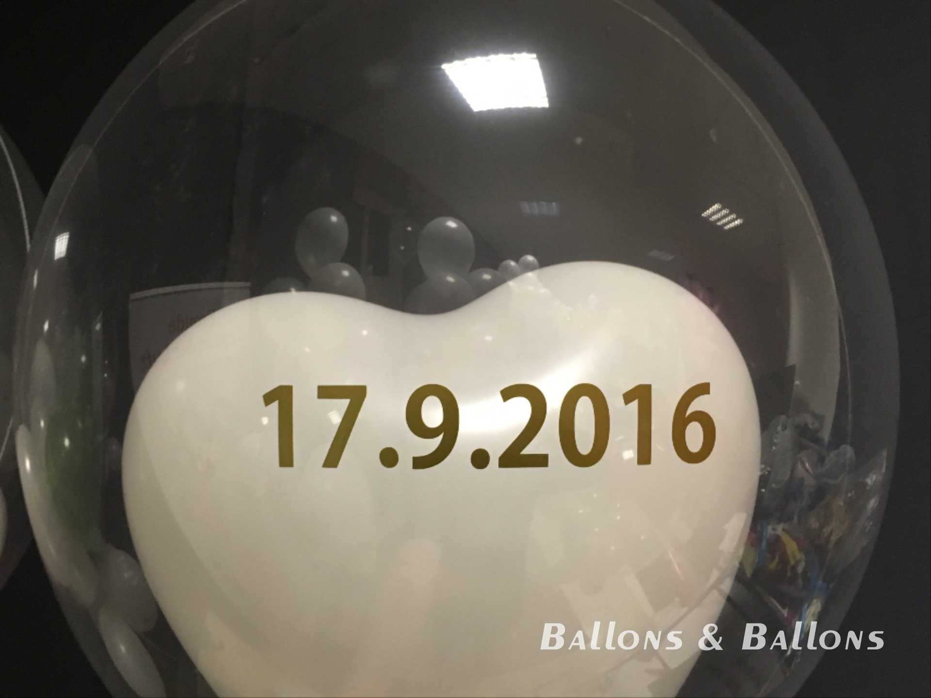 Ein Glasballon mit weißen herzförmigen Ballons in Wien