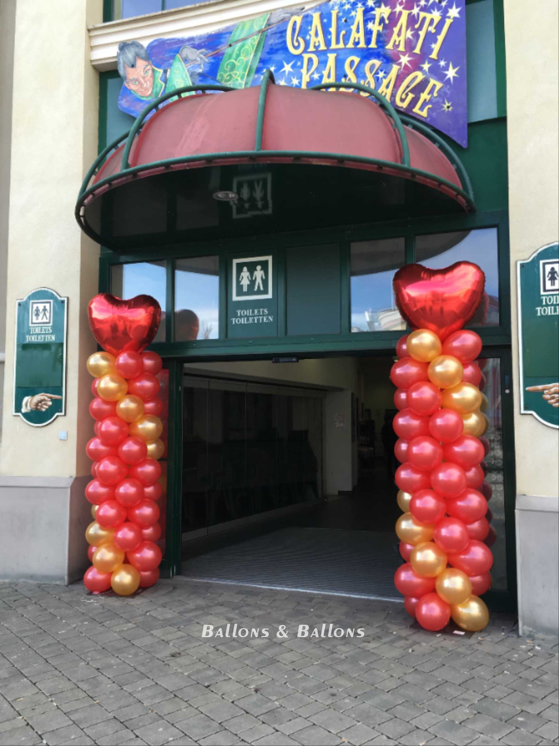 Ein großes Gebäude mit roten Herzballons und einem goldenen Ballonbogen in Wien