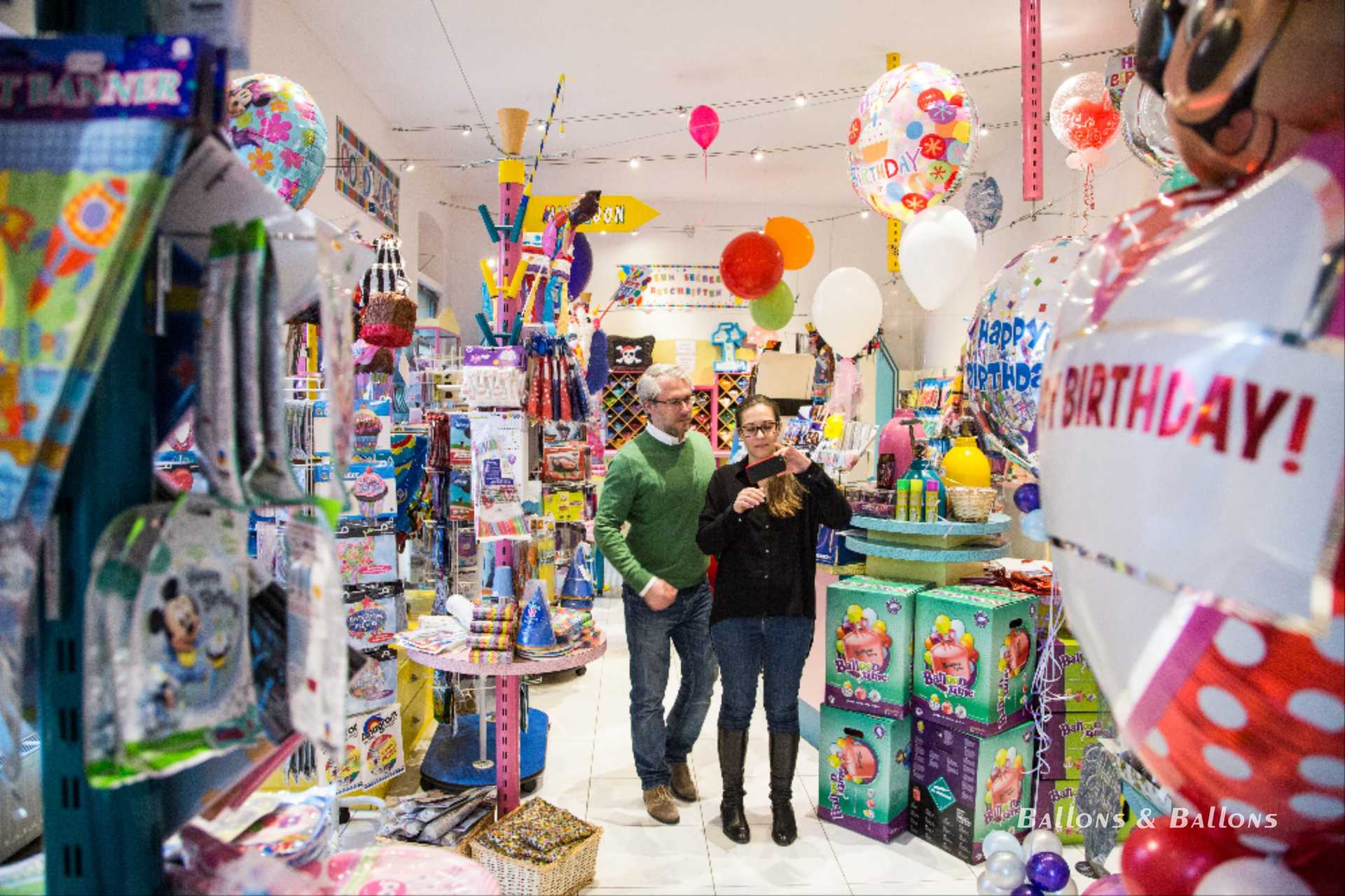 Menschen, die in einem Geschäft mit Ballons und anderen Geschenken einkaufen.