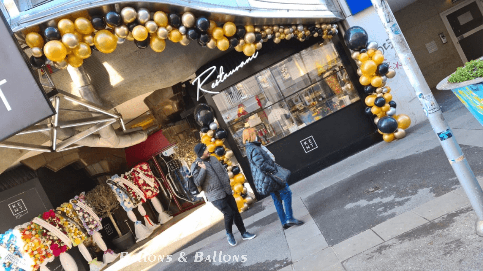 Menschen gehen an einem Geschäft vorbei, das mit Gold- und Schwarzen Ballons dekoriert ist in Wien.