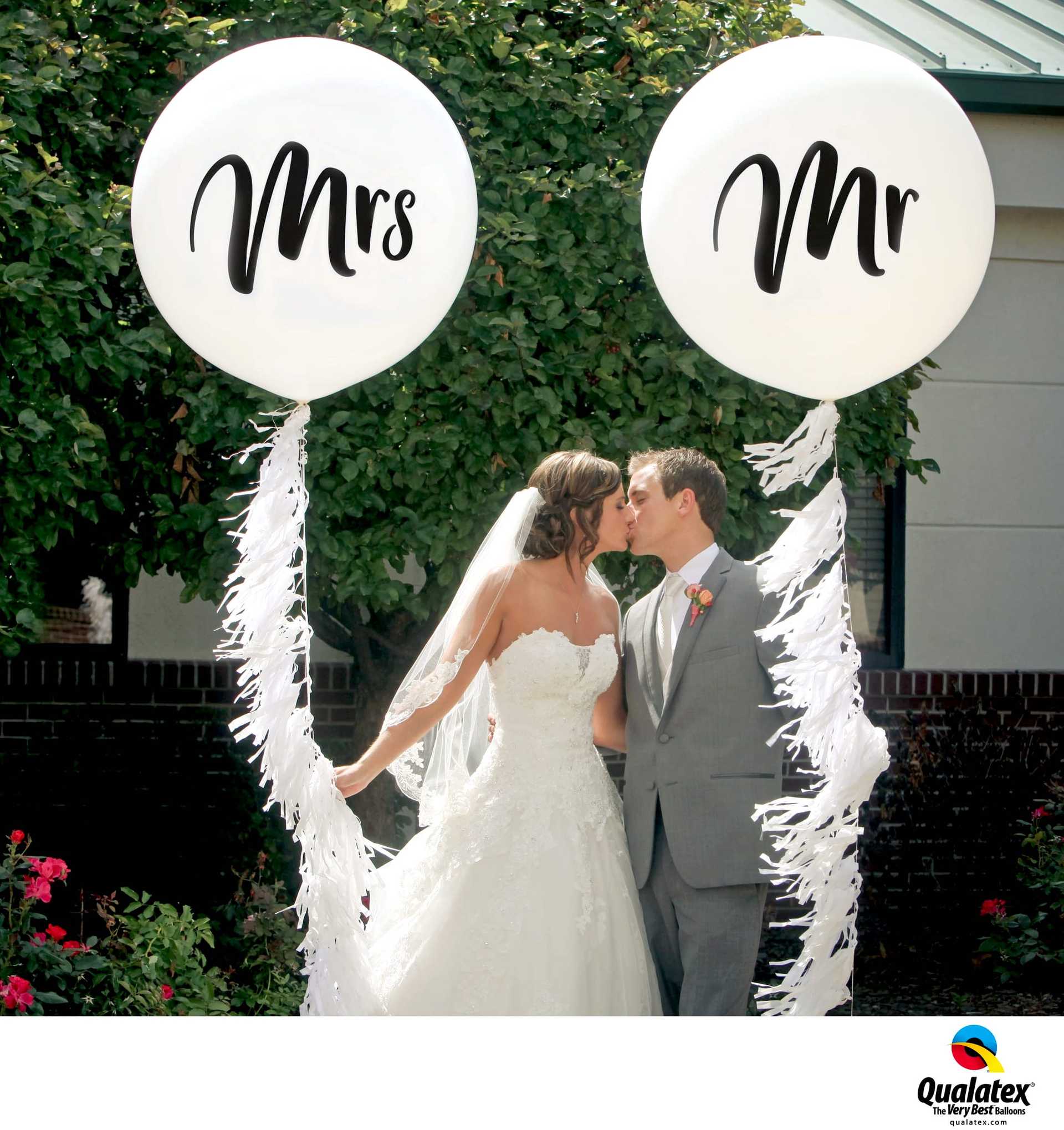 Ein Brautpaar küsst sich und hält Ballons mit der Aufschrift Mr. und Mrs.