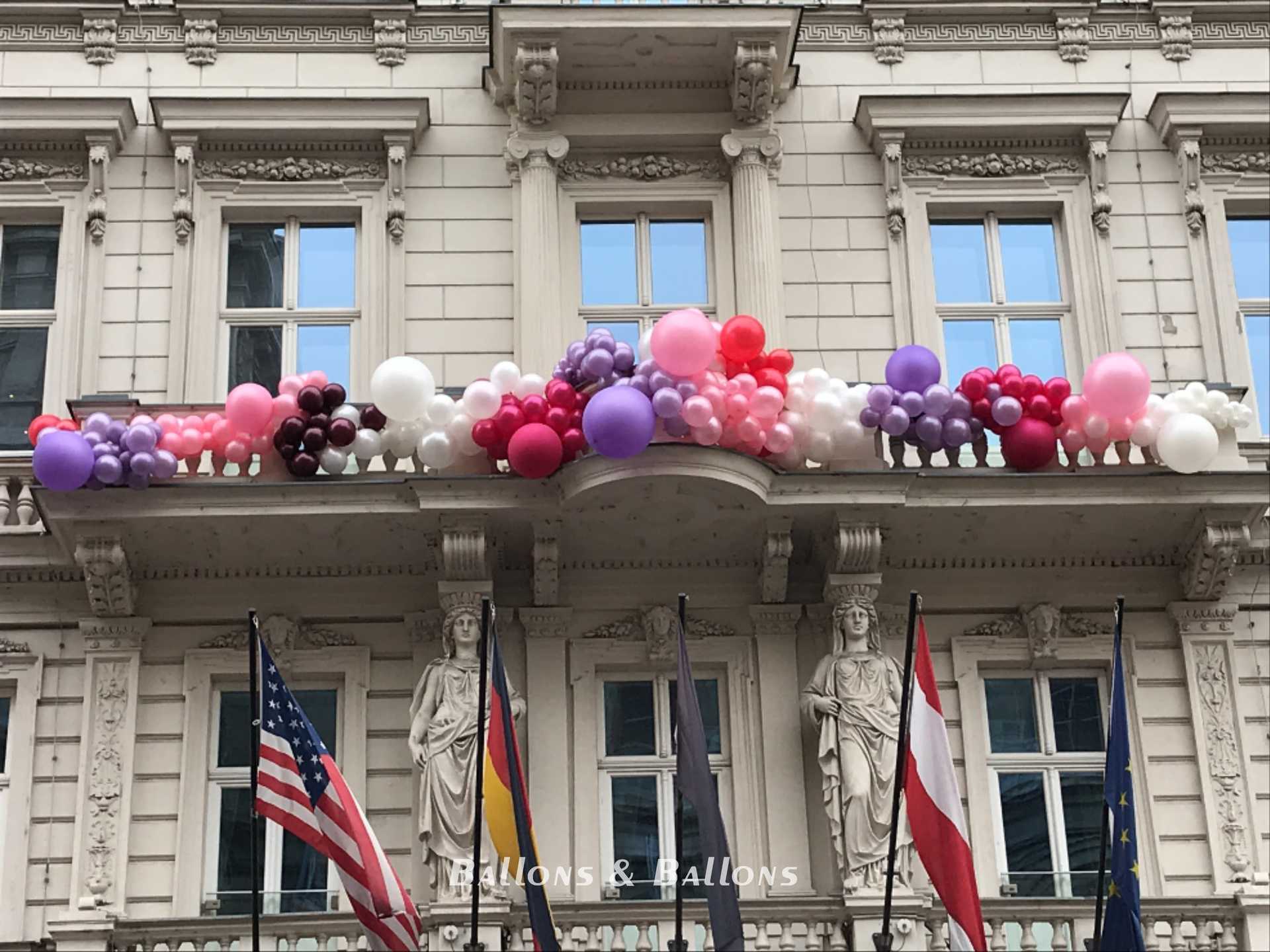 Ballons hängen an einem Gebäude mit vielen Menschen in Wien.