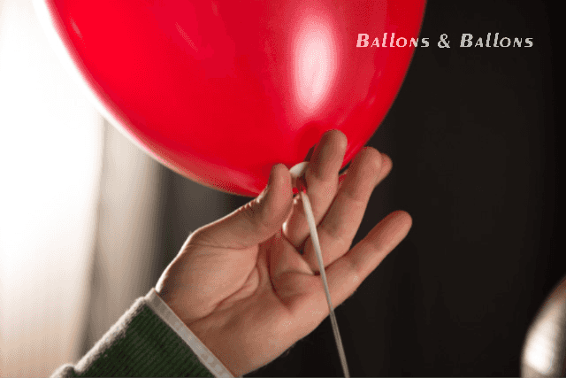 Eine Hand hält einen roten Ballon mit einem Ring darum in Wien.